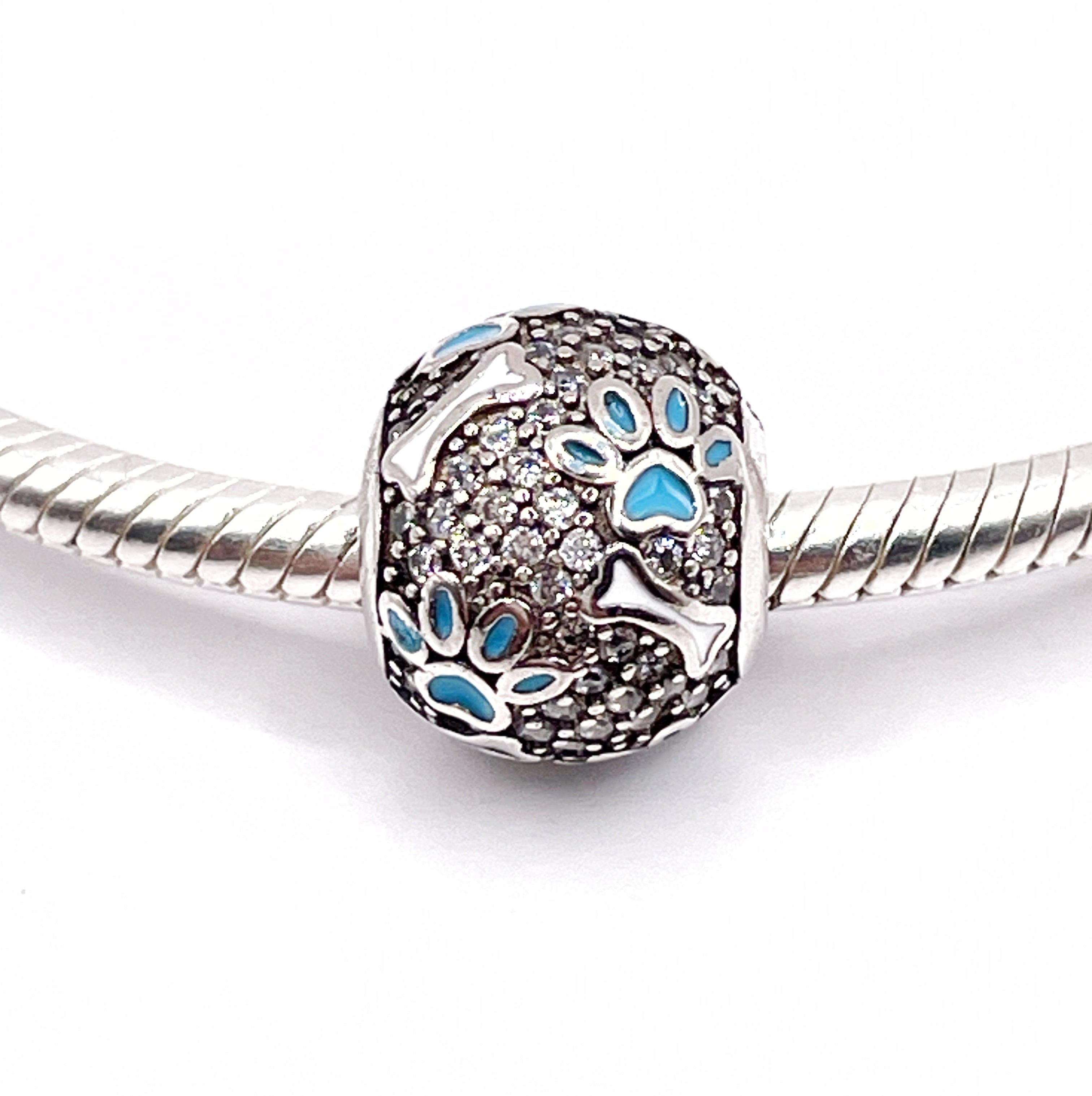 Charm Bolita de circonias con huesos y huellitas celestes